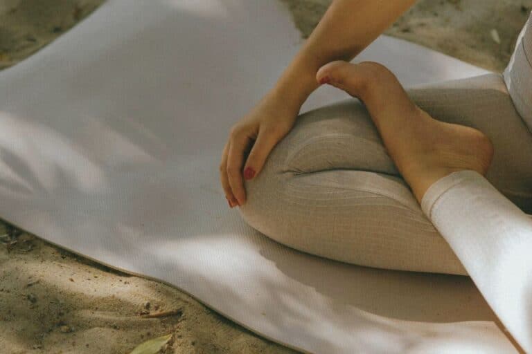 Calming yoga pose on a white mat outdoors, emphasizing mindfulness and stress relief.