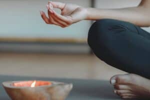 Calm woman practicing yoga and meditation with yoga pose, candle for mindfulness, and peaceful ambiance. Focus on mental wellness, stress relief, and mindfulness techniques for relaxation.